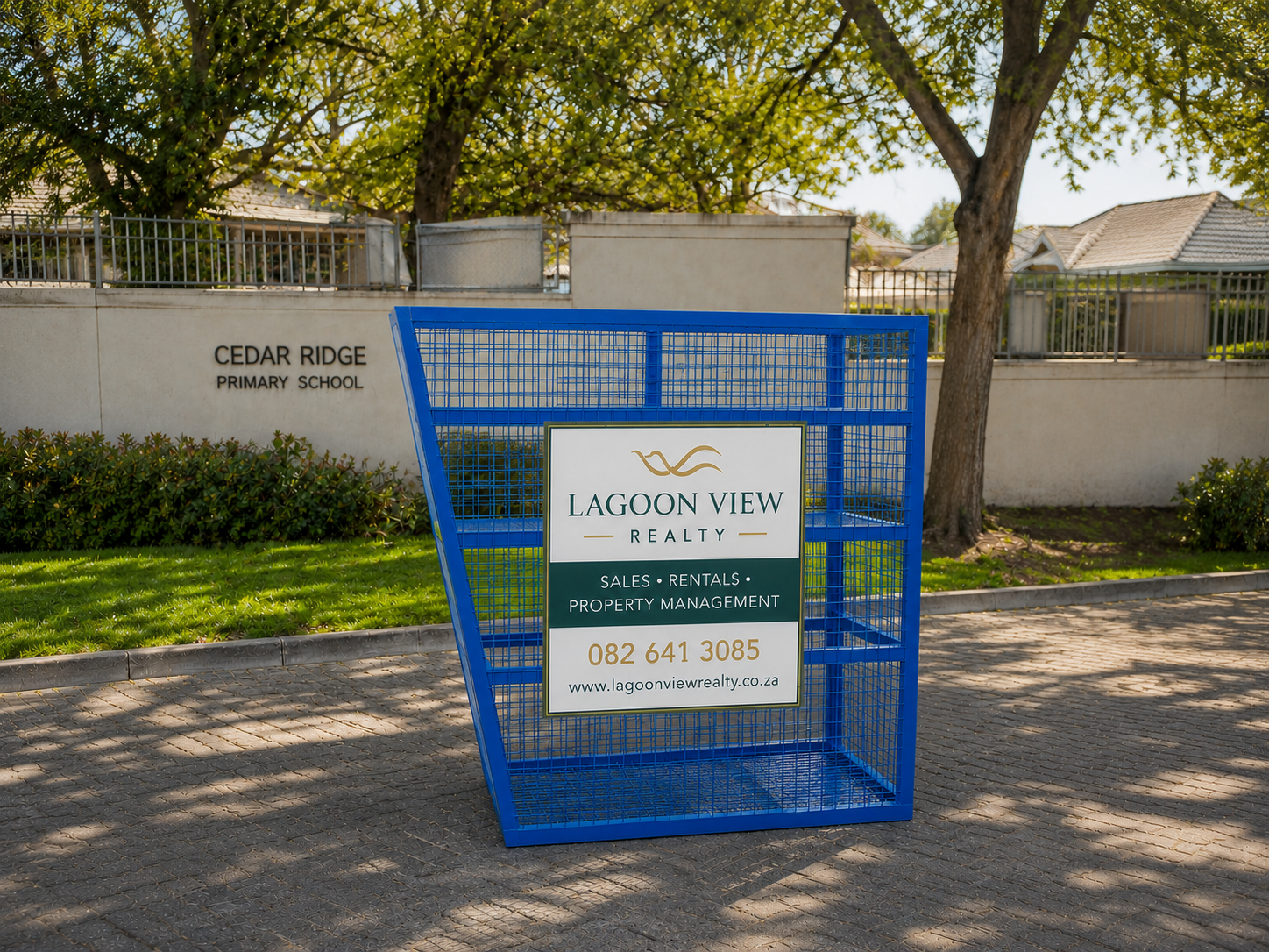 Blue recycling cage carrying Lagoon View Realty advertising outside Cedar Ridge Primary School.